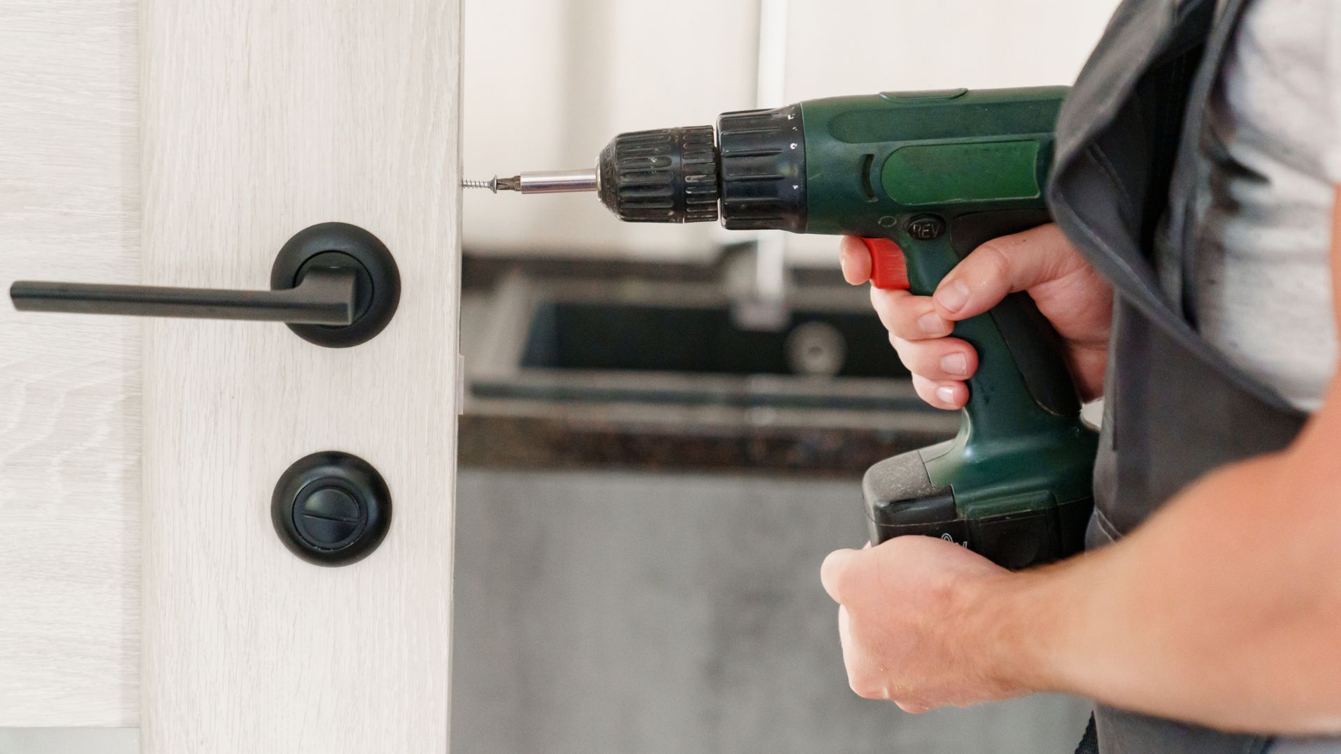 A man holding a drill and a screwdriver