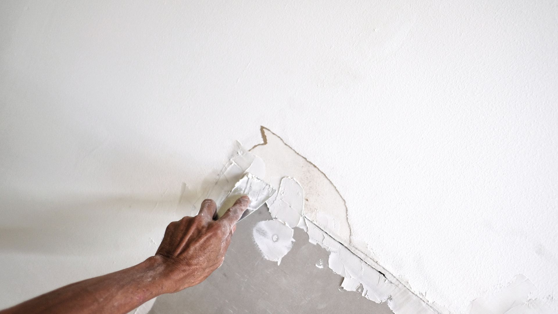 A person painting a wall with a paint roller